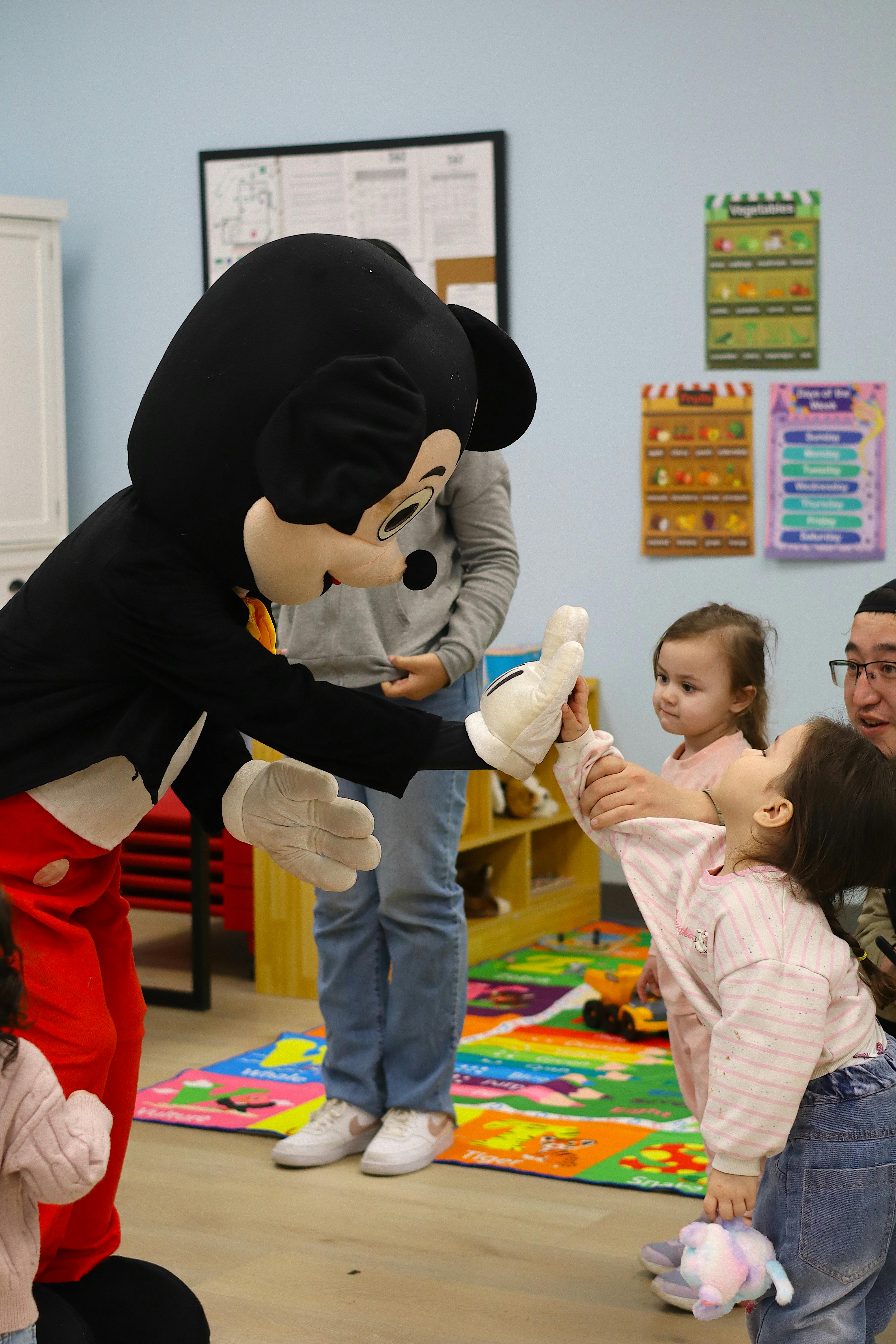 Mickey Mouse mascot high-fiving a child in a classroom