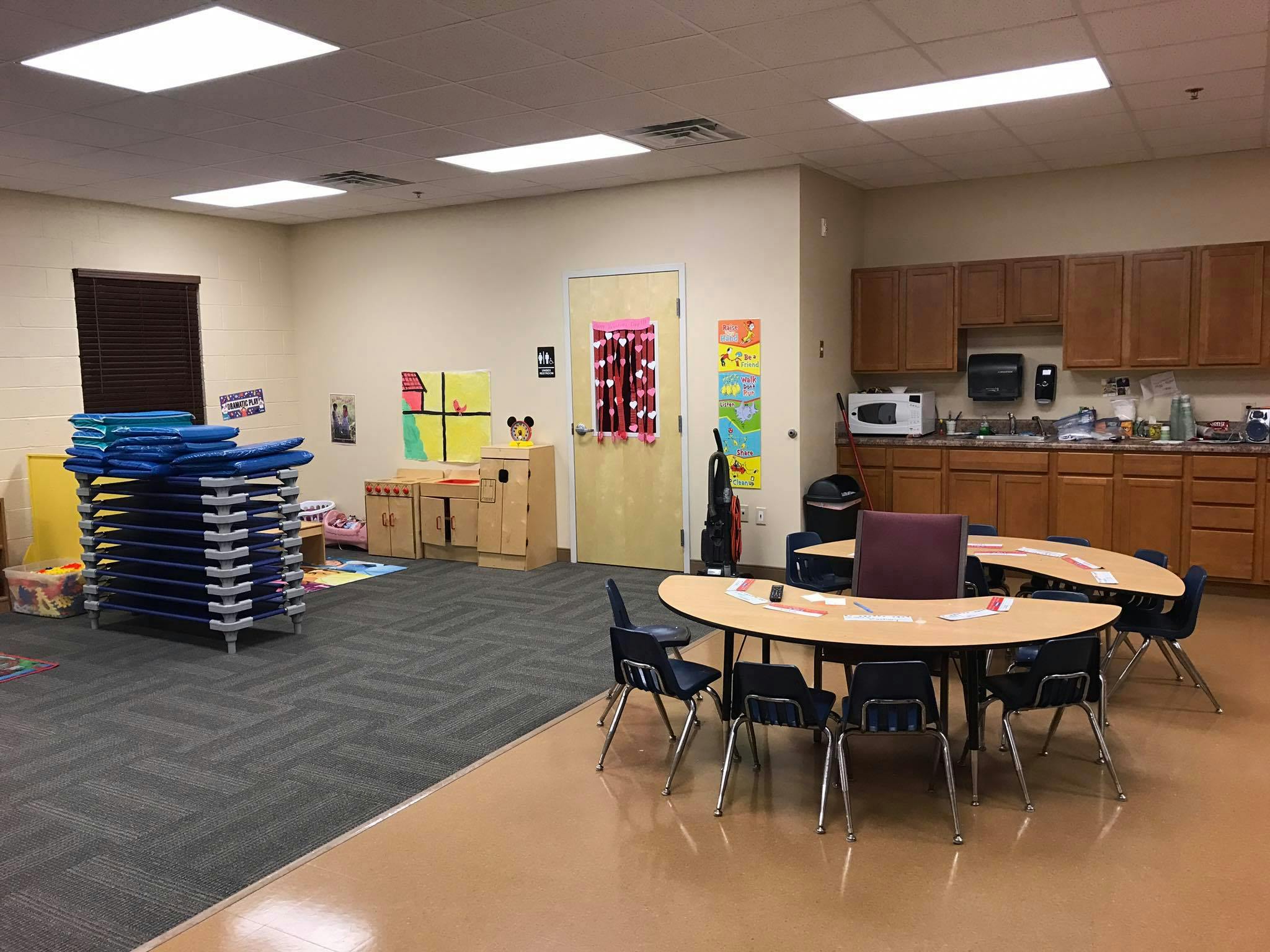 Classroom with tables, chairs, and stacked cots