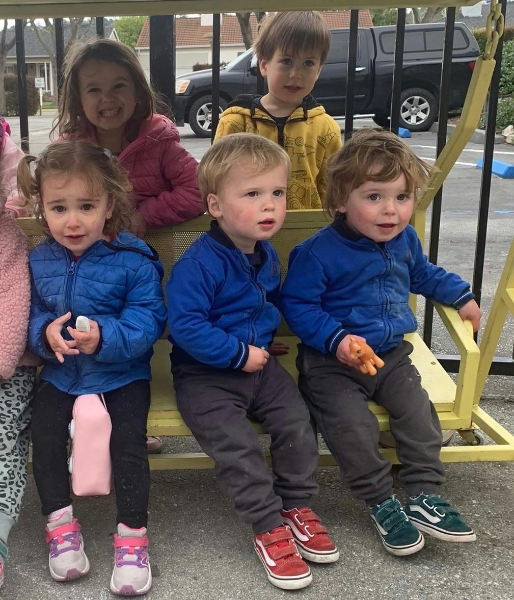 Five children sitting on a yellow bench