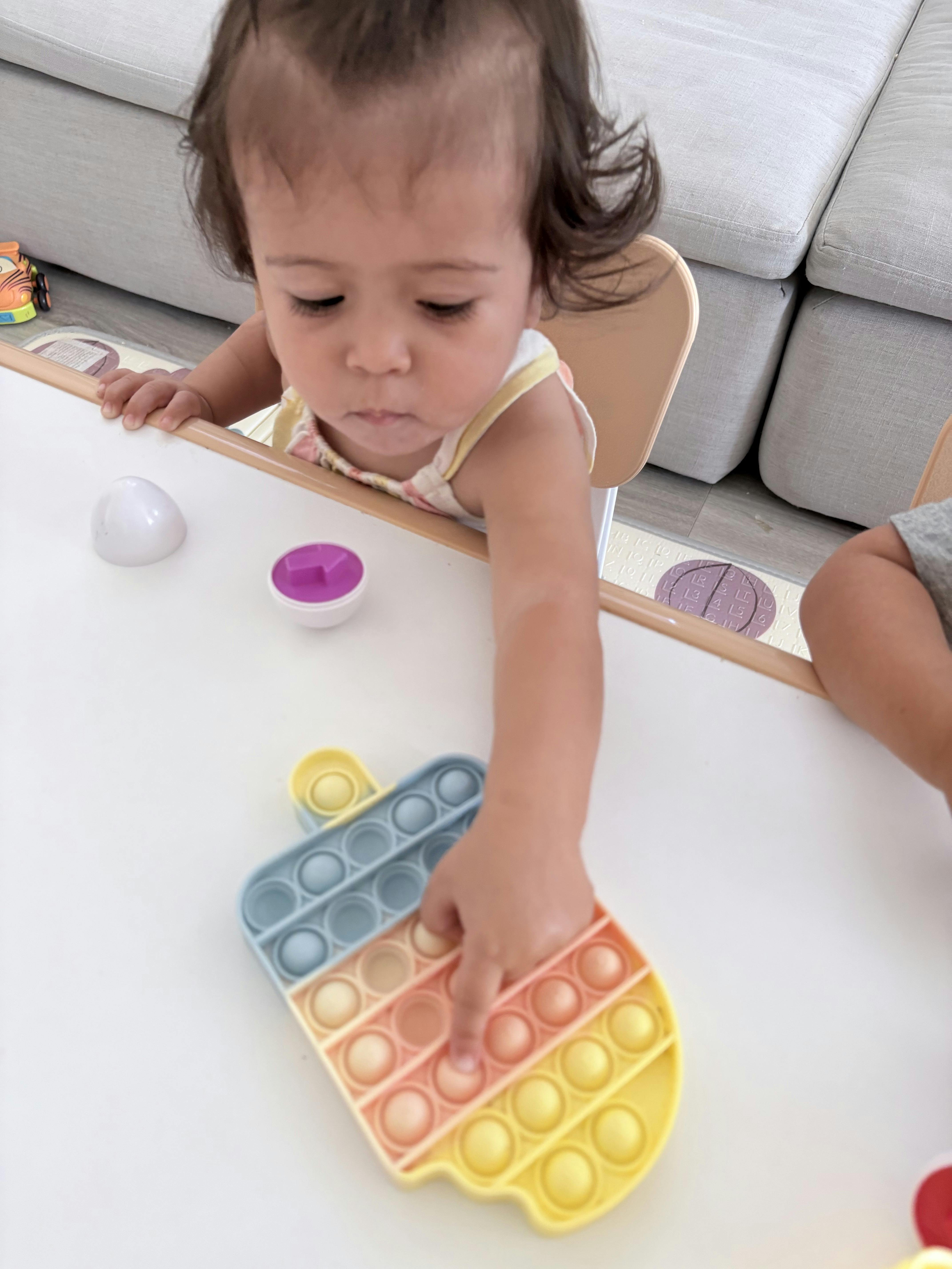 Child playing with a sensory pop-it toy at a table
