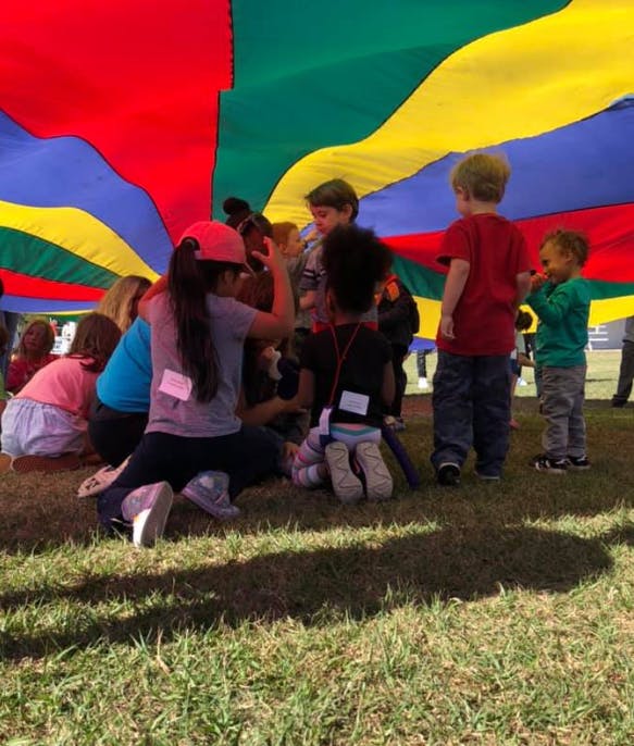 Children playing under a colorful parachute