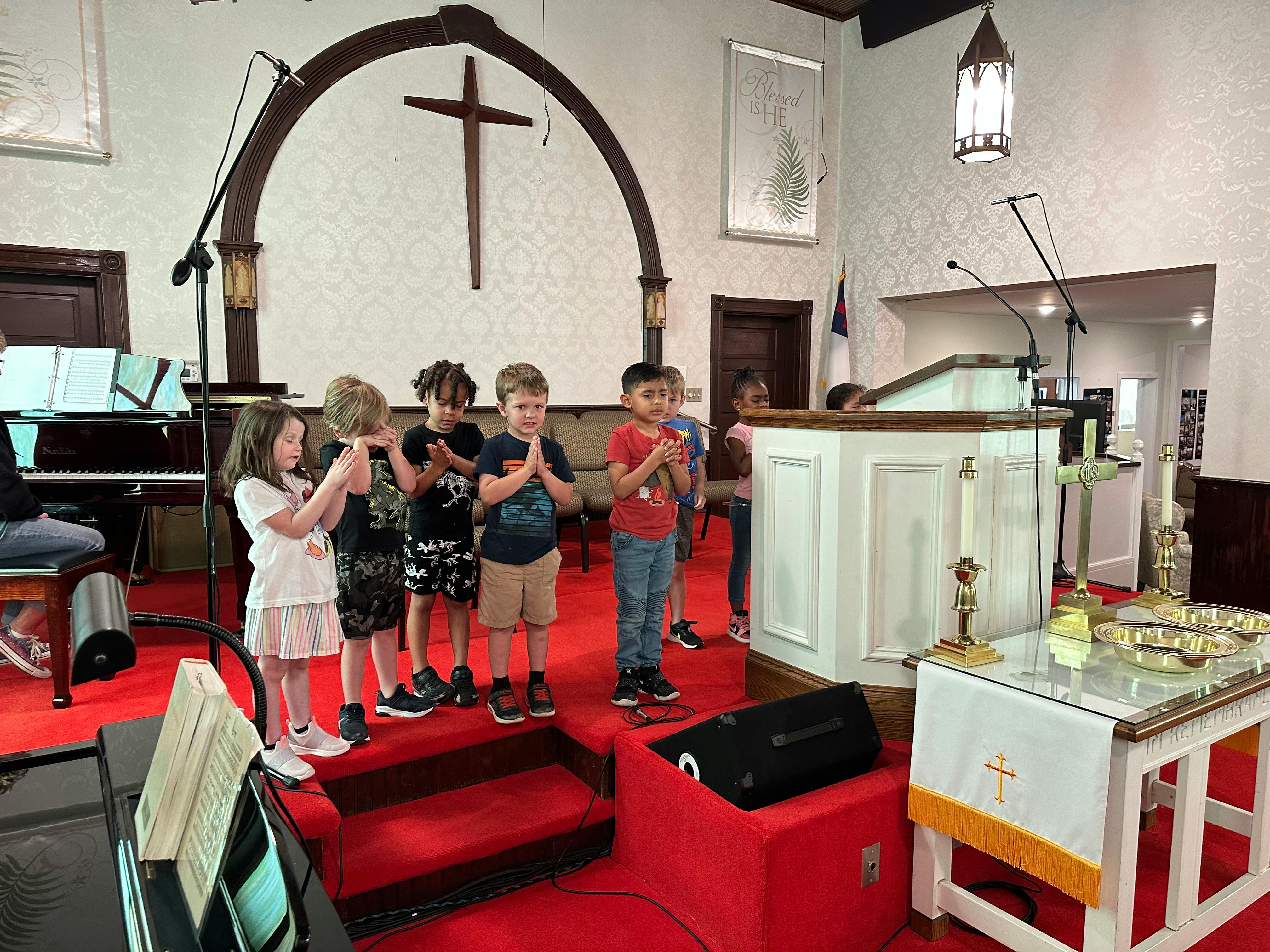 Children standing with hands together in a church