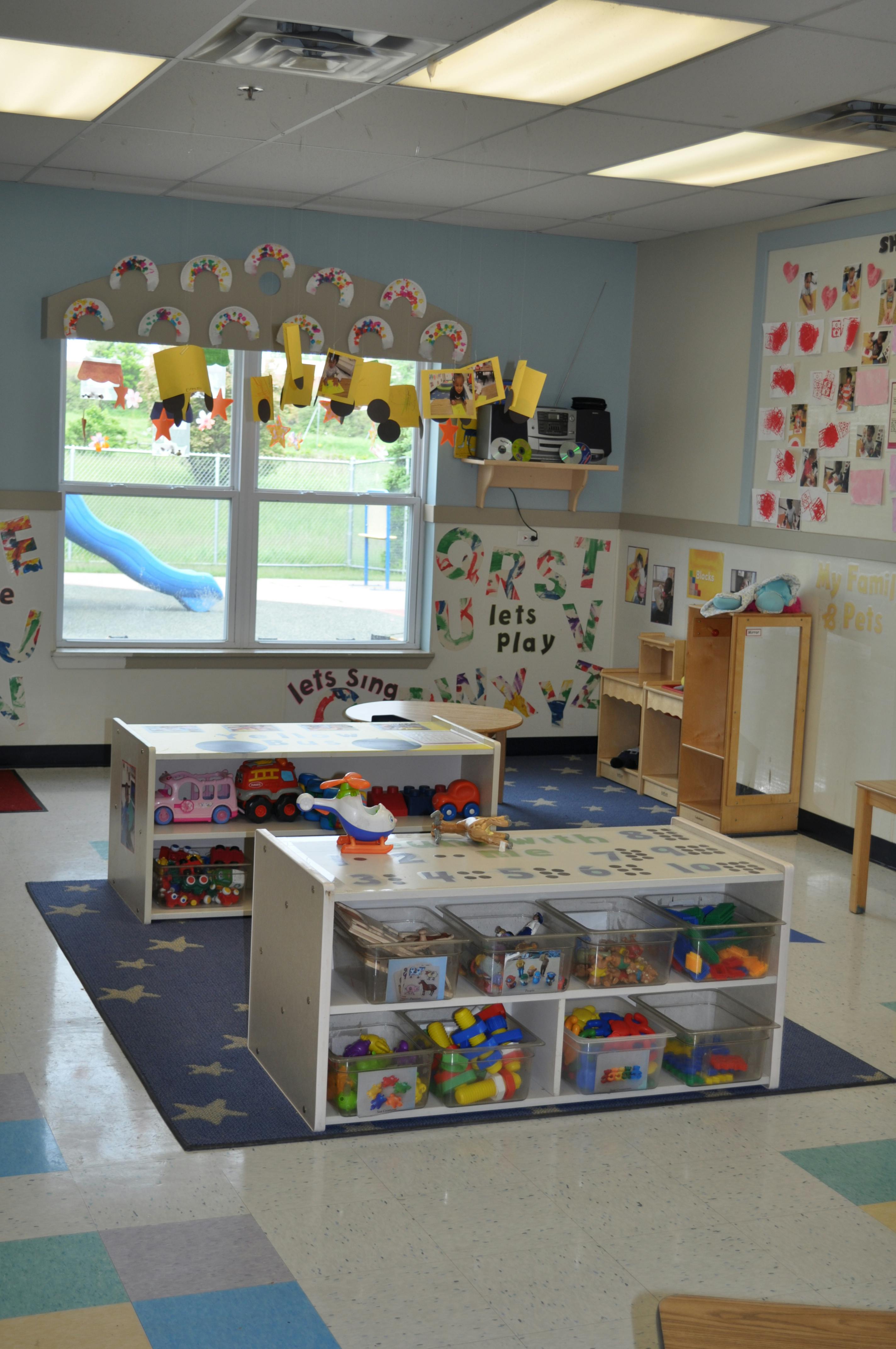 Classroom with shelves of toys, decorations, and a window looking out at a slide