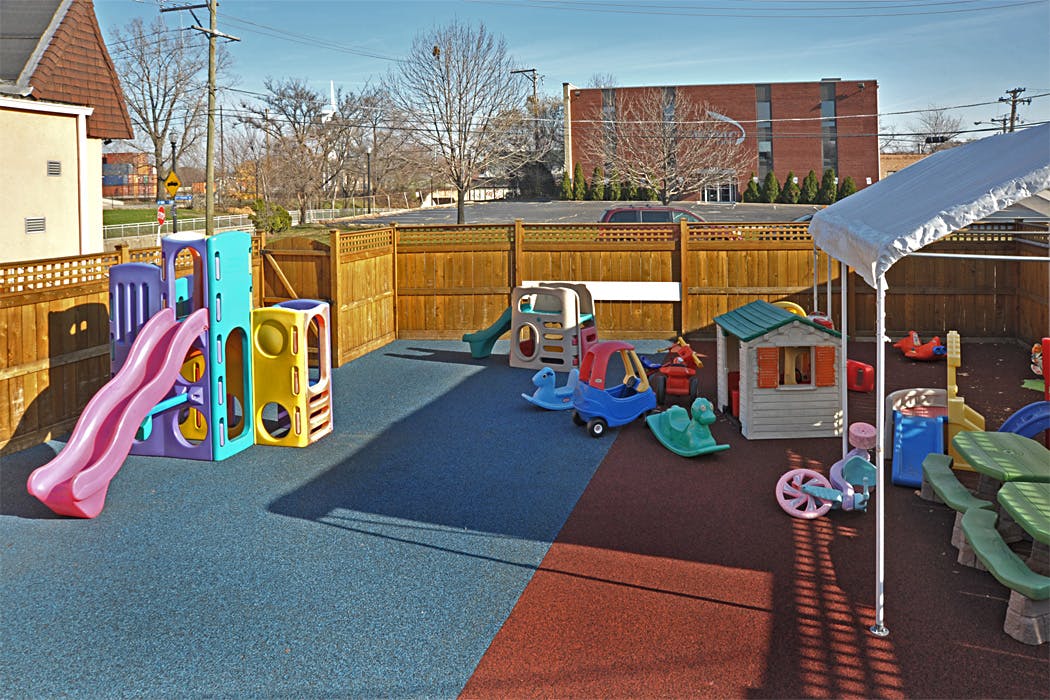 Outdoor playground with slides, playhouses, and ride-on toys on a soft surface