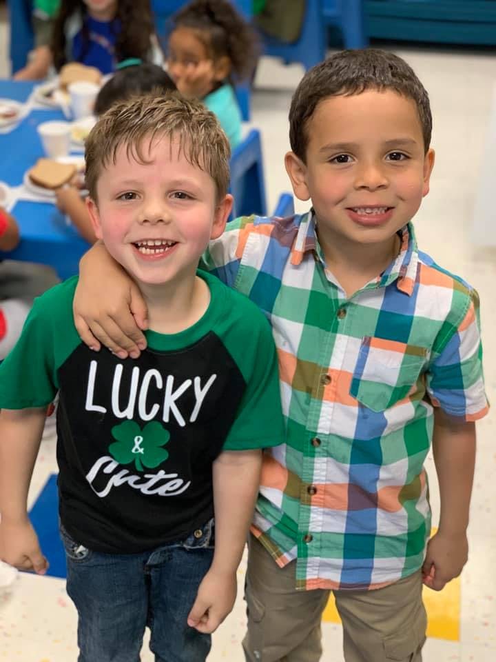 Two children standing together, one with arm around the other