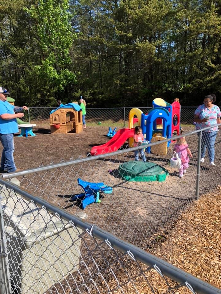People and children on a playground with play structures