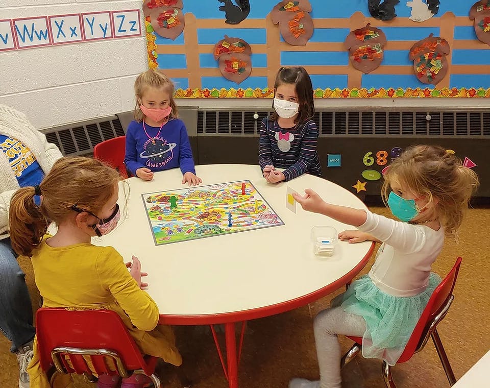Children wearing masks playing a board game at a table