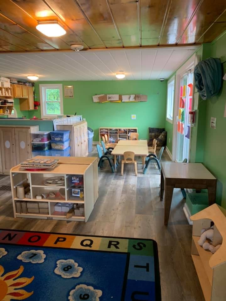Classroom with small tables and chairs, storage units, and a colorful rug
