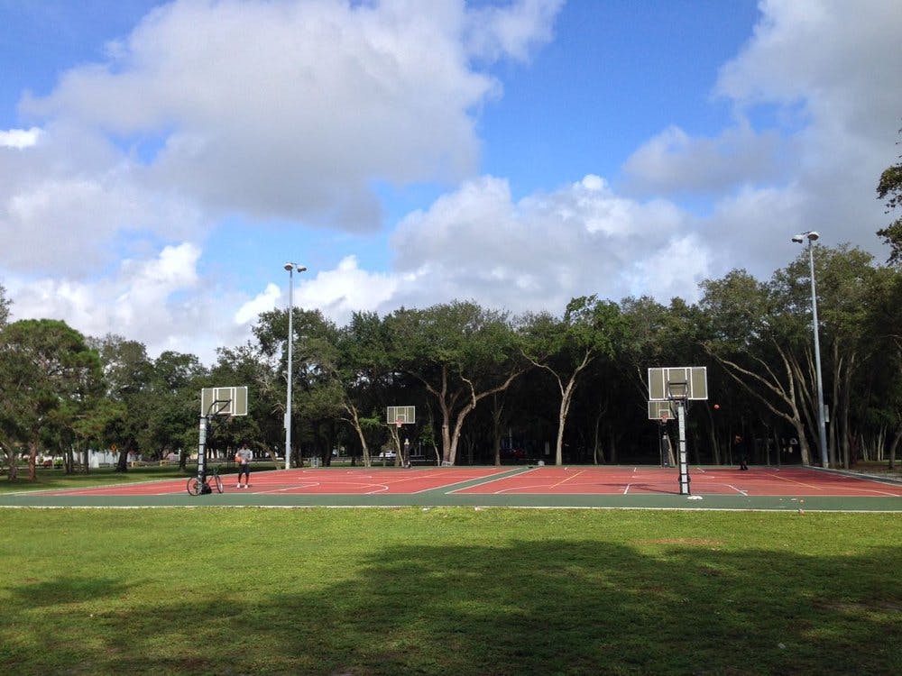 Outdoor basketball court with red surface and green grass