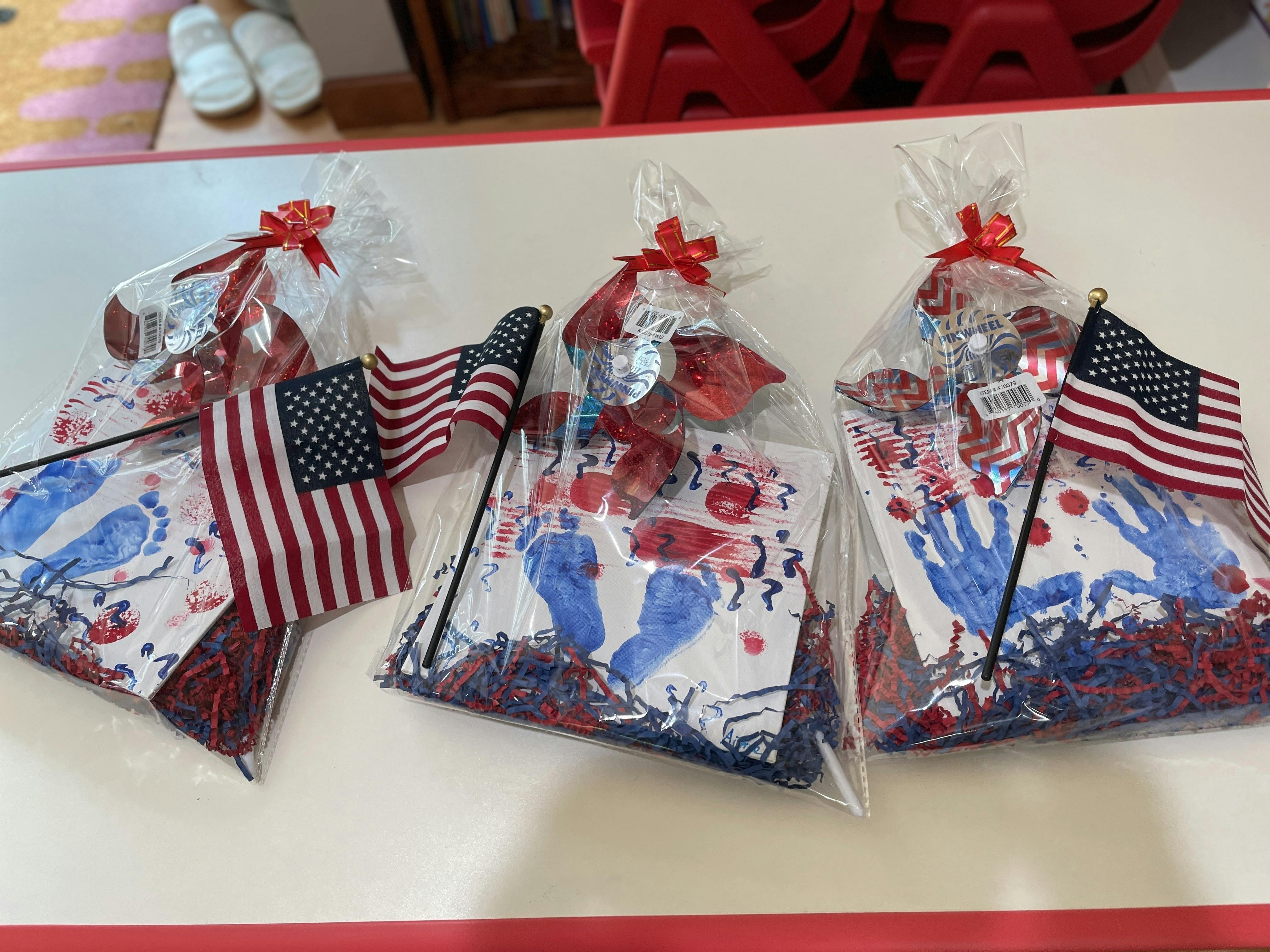 Three clear bags with American flags and paper with handprints and footprints