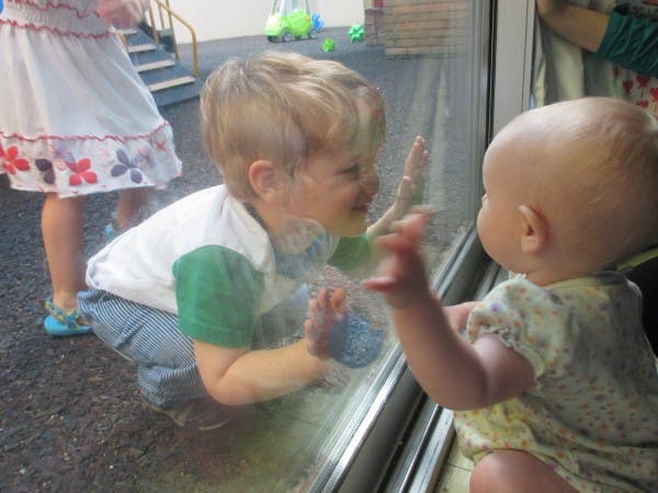 Child and baby looking at each other through a window