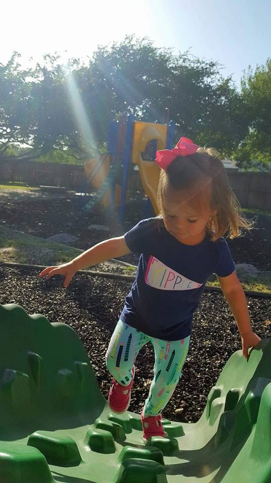 Child walking on a green playground climbing structure