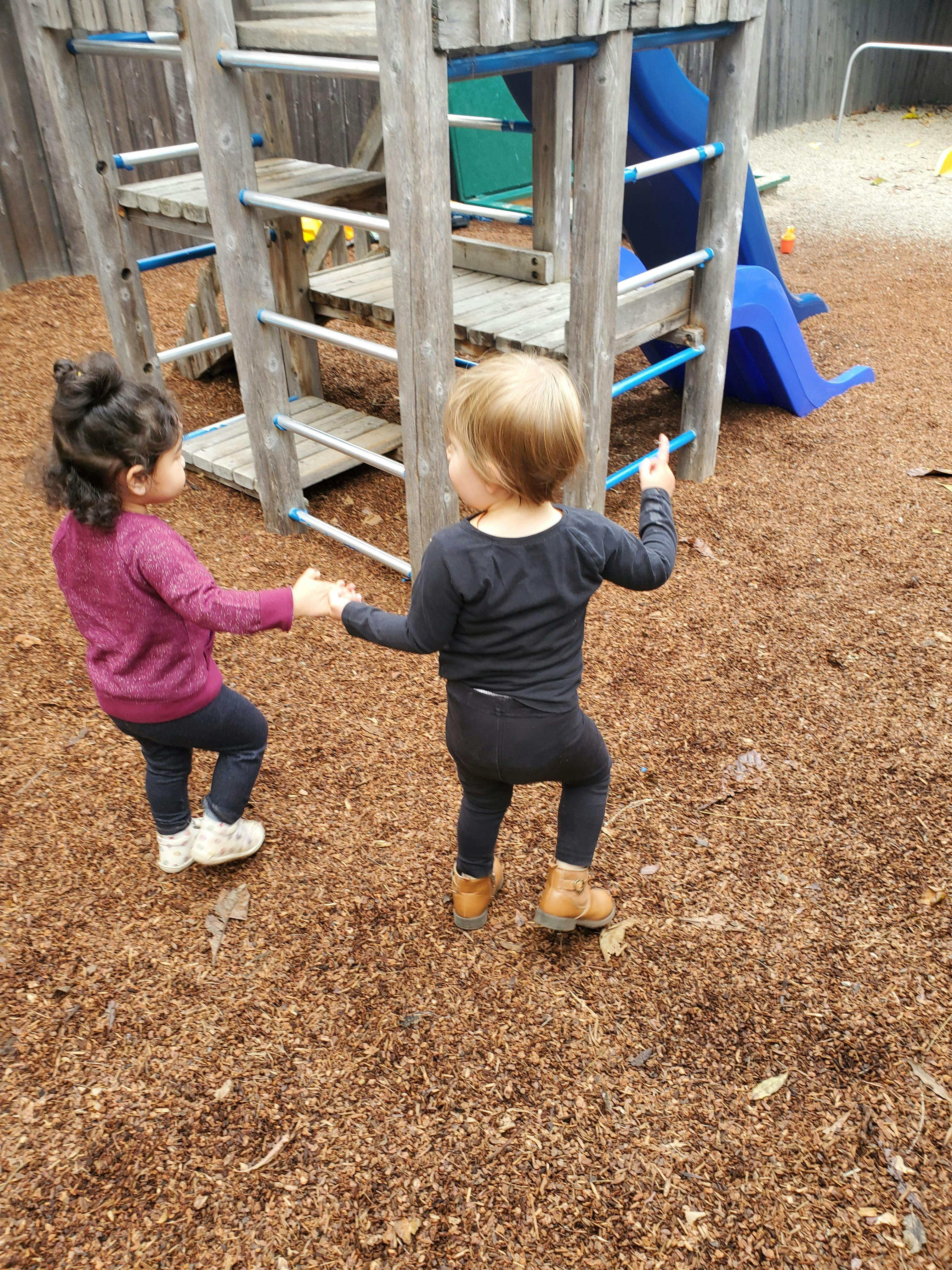 Two children holding hands on a playground