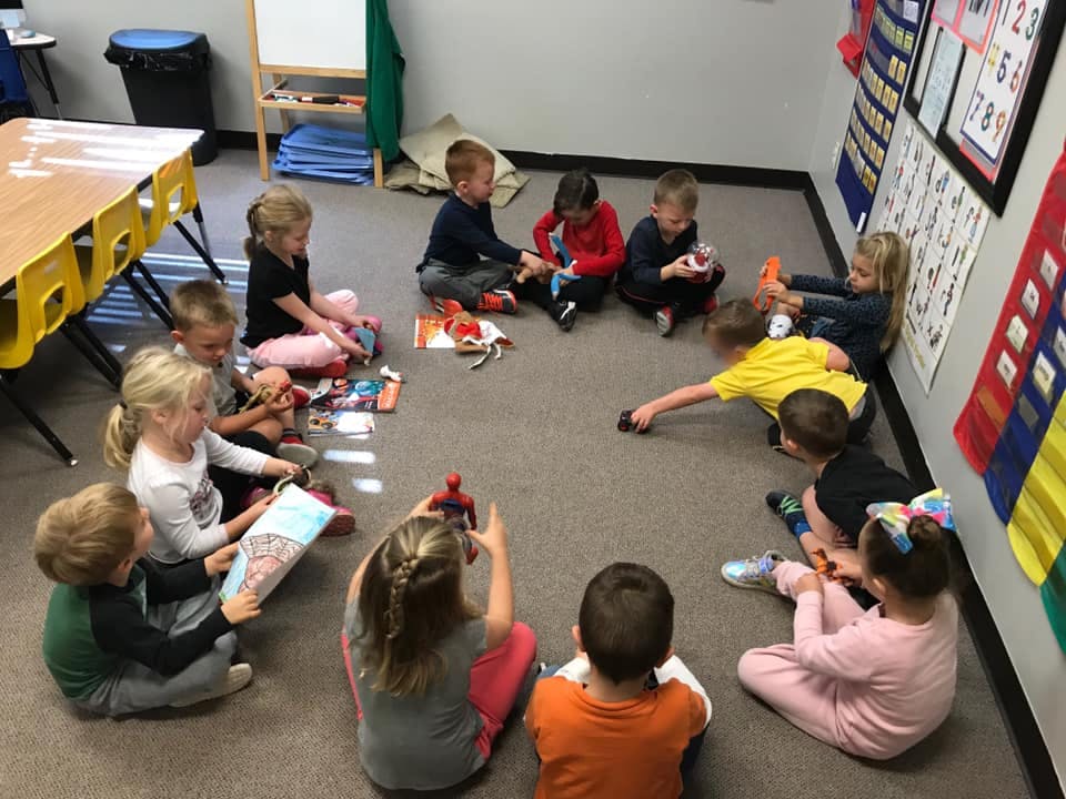 Children sitting in a circle on the floor playing with toys