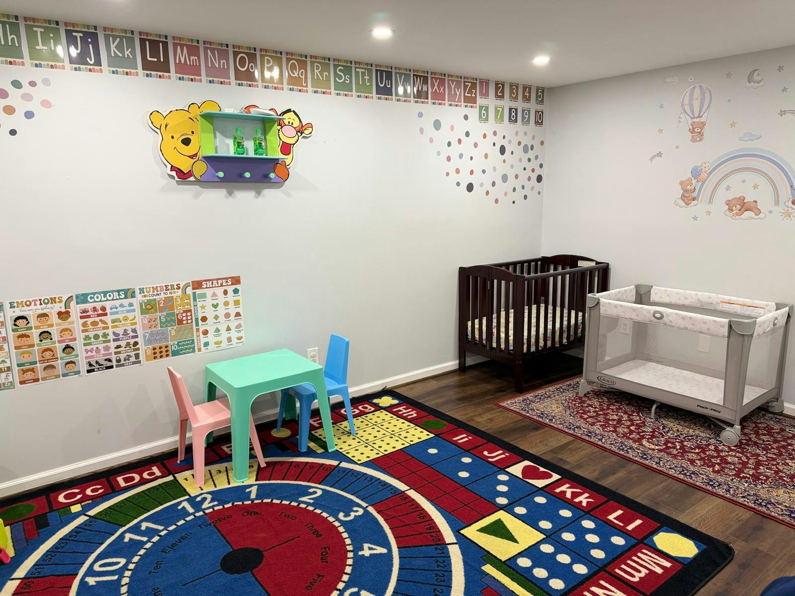 Child's playroom with cribs, small table and chairs, and educational posters