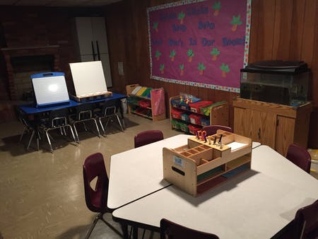 Classroom with tables, chairs, easels, and storage shelves