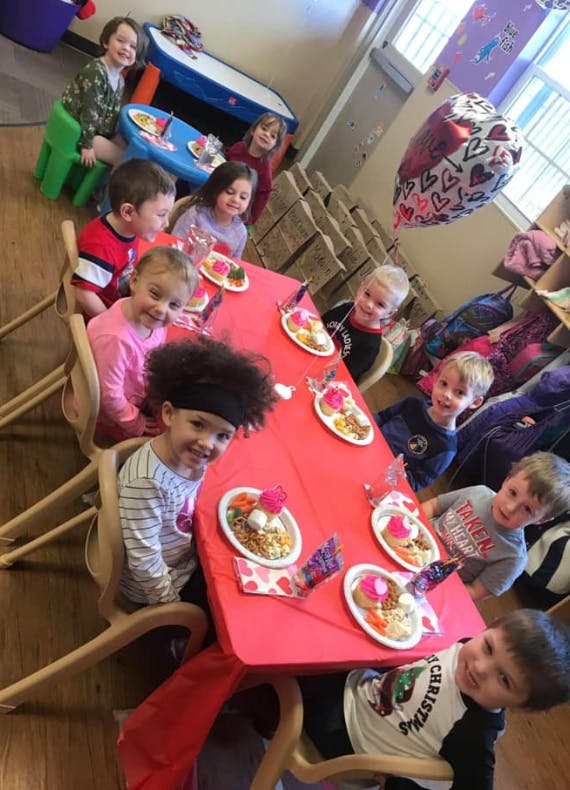 Children sitting around a table with plates of food
