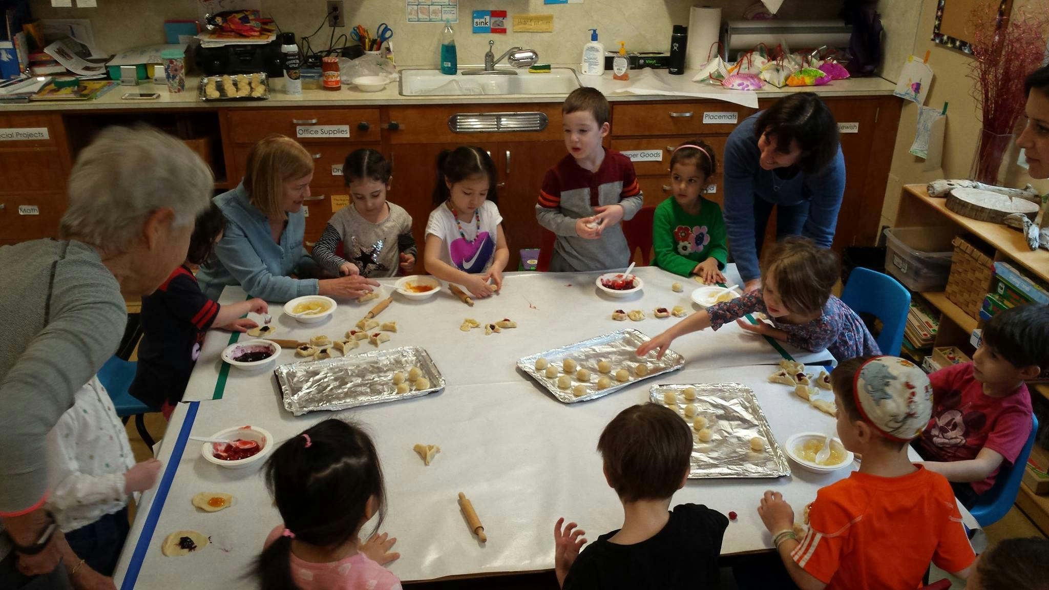 Adults and children around a table making cookies