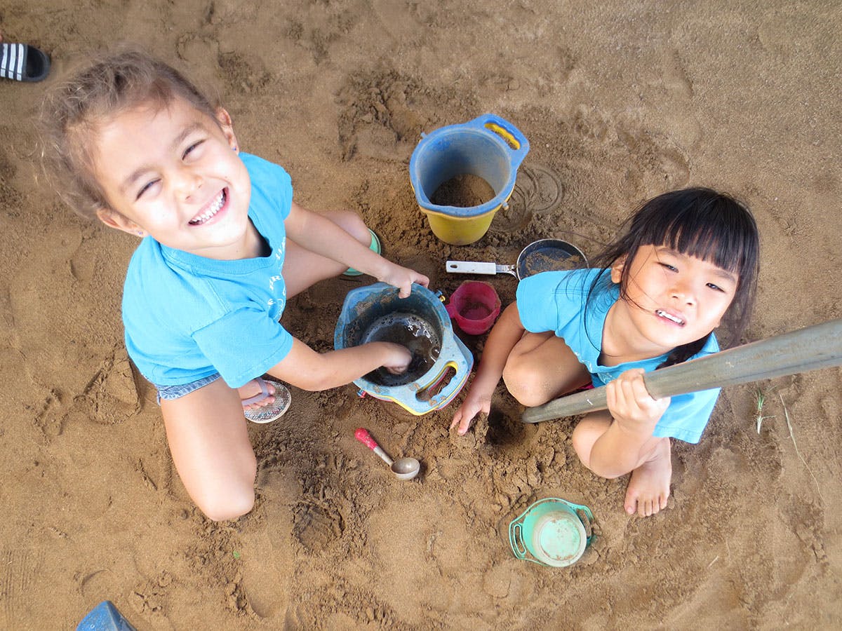 Two children playing in sand with buckets and shovels
