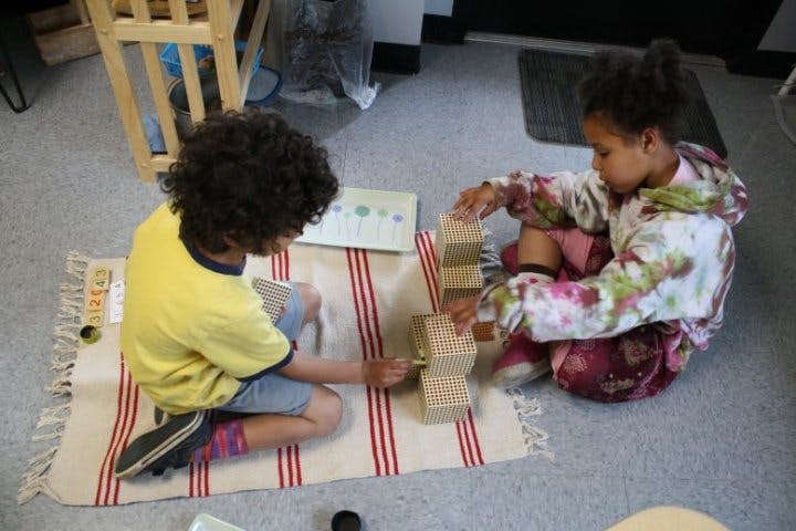 Two children playing with blocks on a rug
