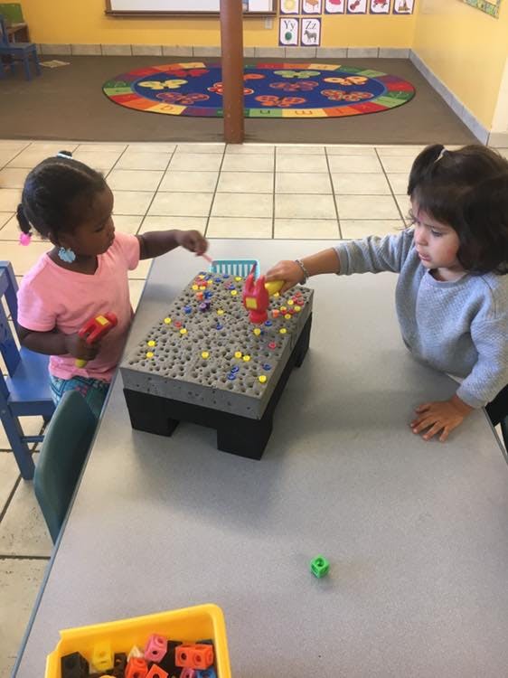 Two children playing with a pegboard toy on a table