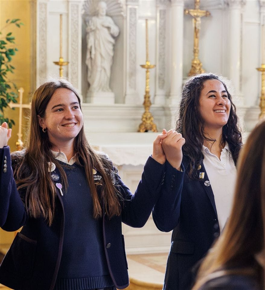 Two teens holding hands in a church, smiling