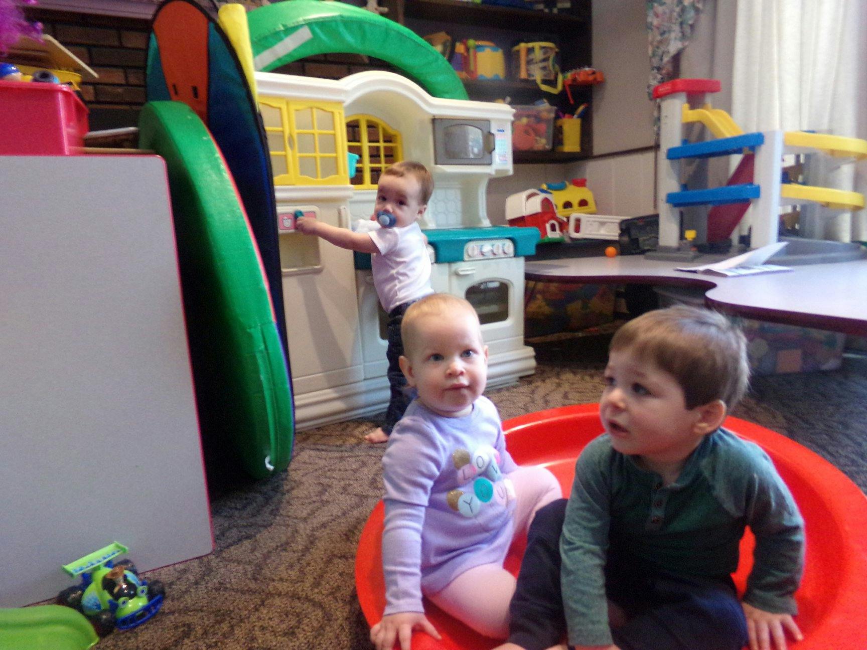 Three children playing in a room with toys