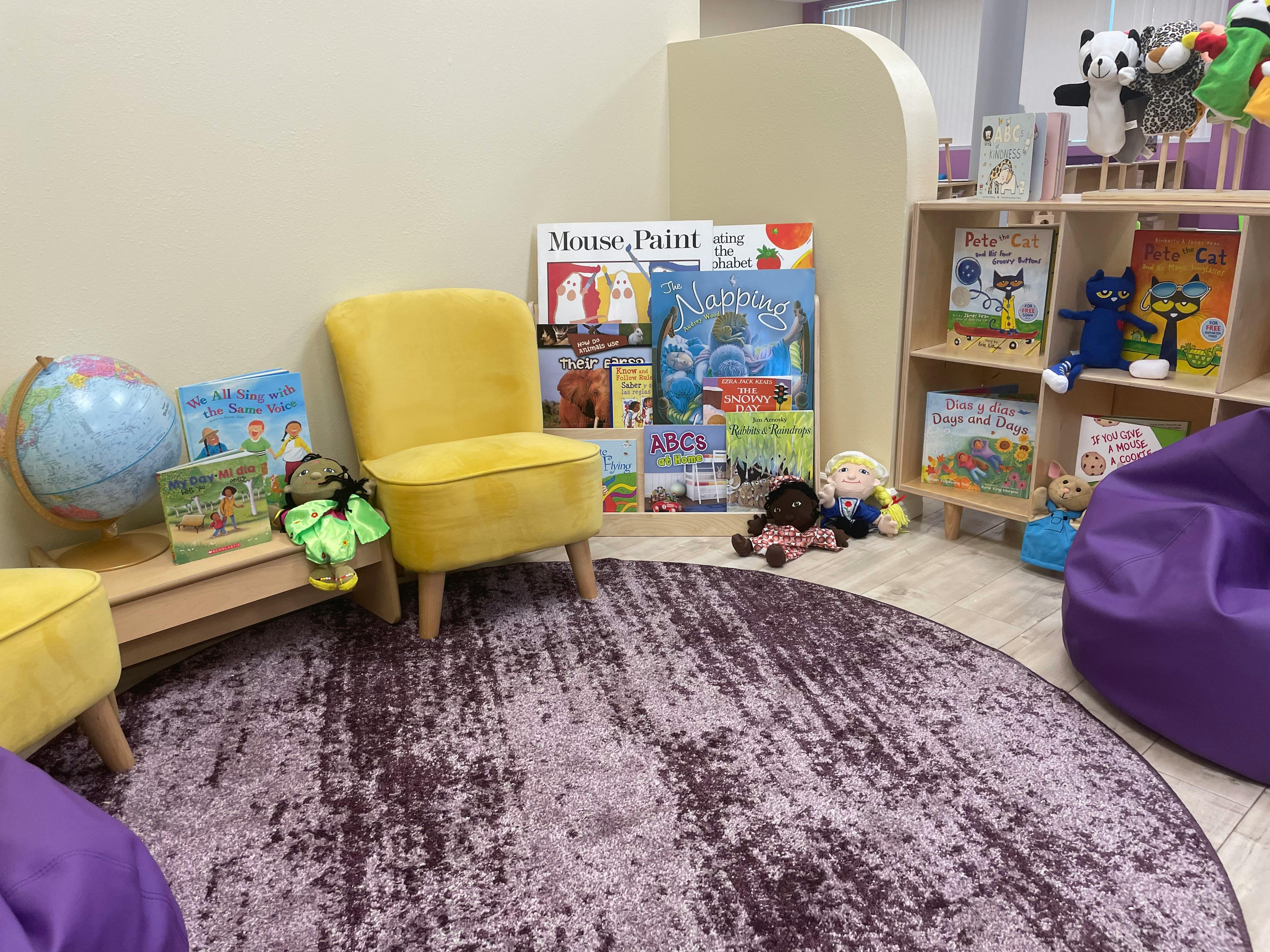 Children's reading nook with yellow chairs, books, and a globe