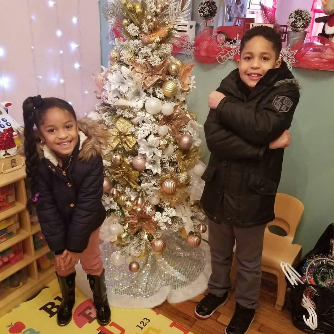 Two children standing in front of a decorated Christmas tree
