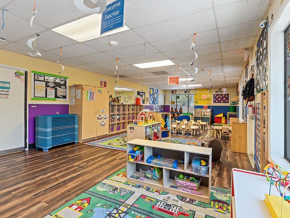 Colorful preschool classroom with play mats, small tables, and shelves of toys