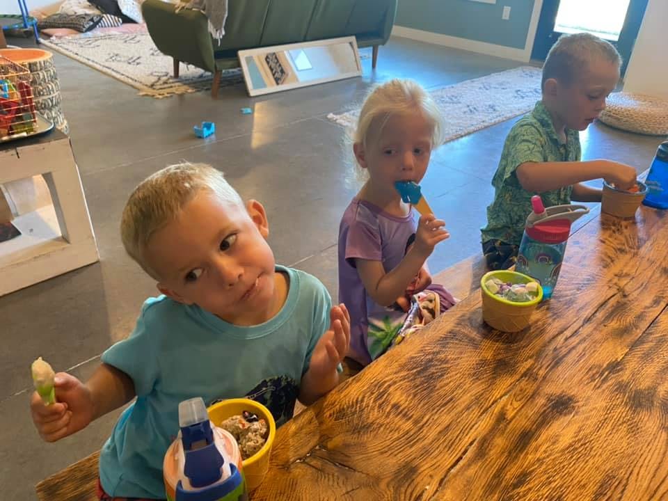 Three children sitting at a wooden table