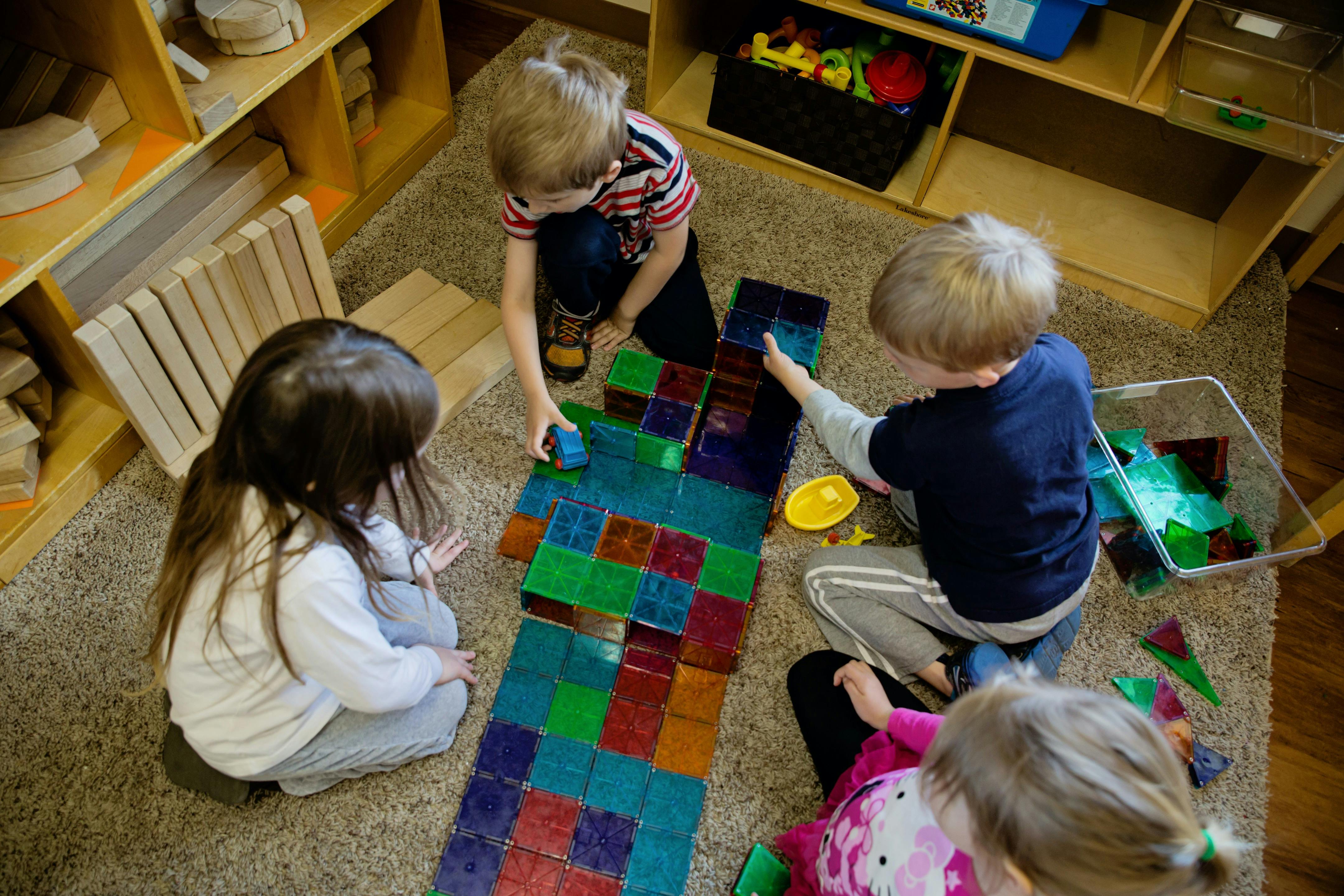 Children playing with colorful magnetic tiles on a rug