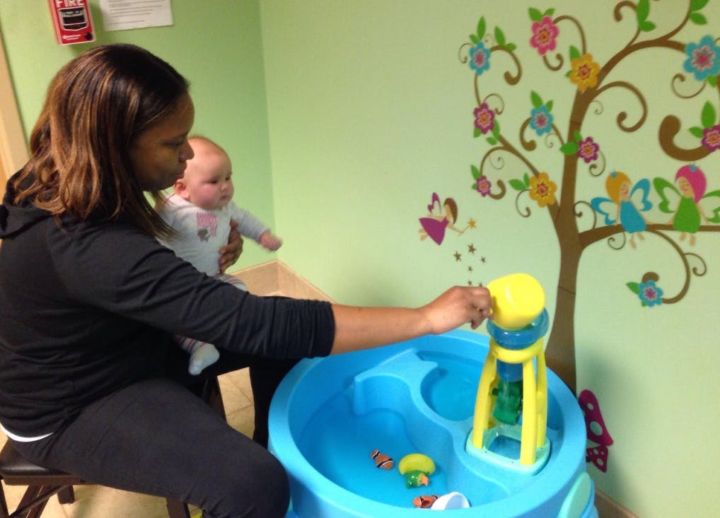 Person holding a child and playing with a water table toy