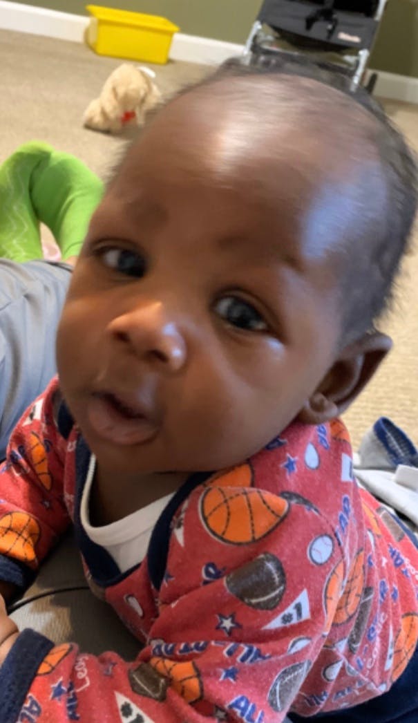 Close-up of a baby wearing a red shirt with sports balls