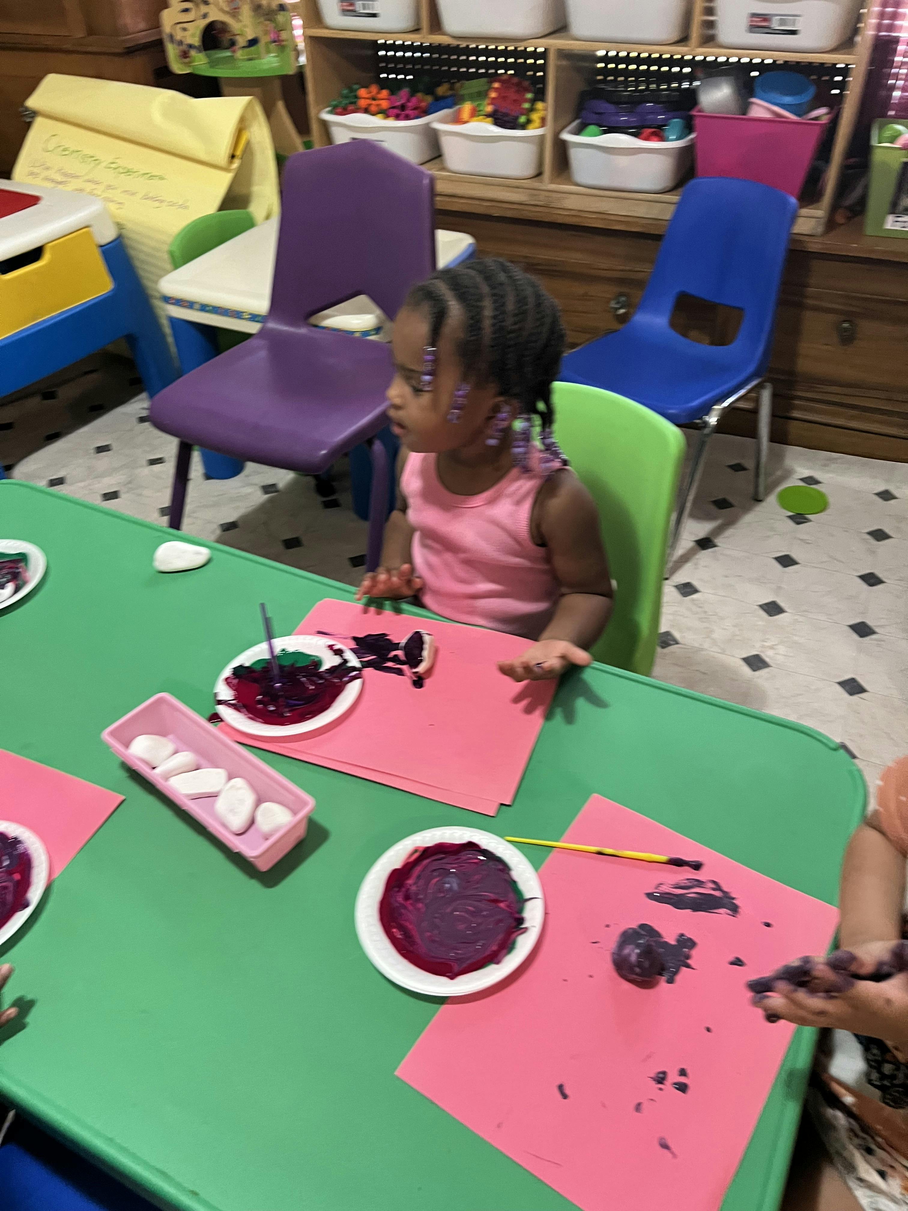 Child sitting at a table with paint and paper