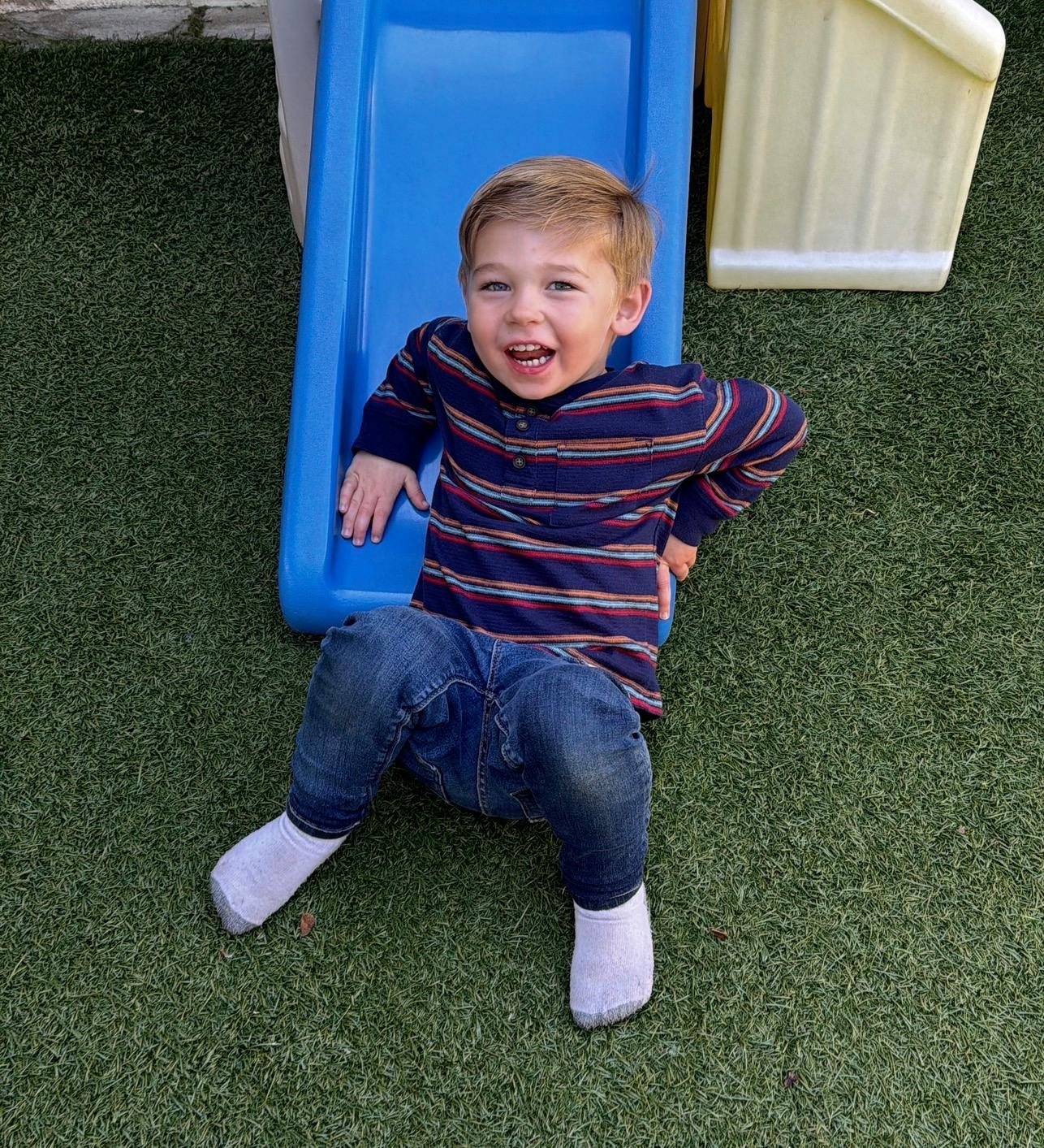Child sitting at the bottom of a plastic slide