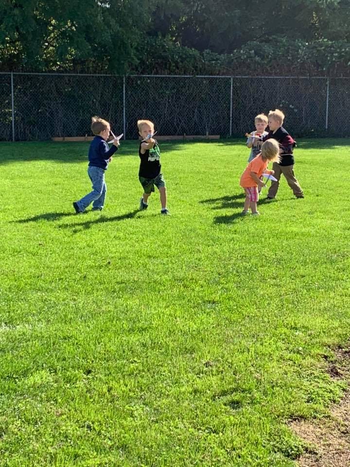 Children playing with toy airplanes on a grassy field