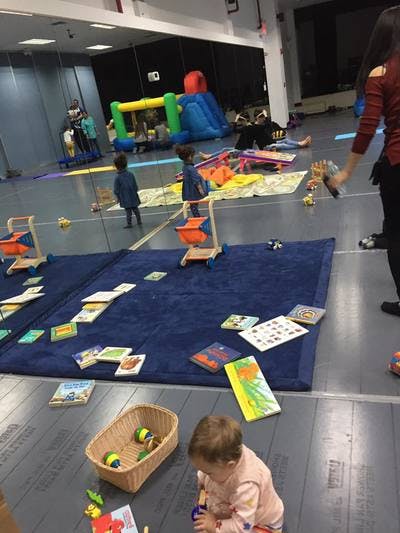 Children playing with toys and books on mats in a large room