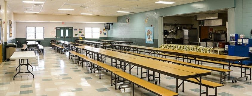 Empty school cafeteria with long tables and benches