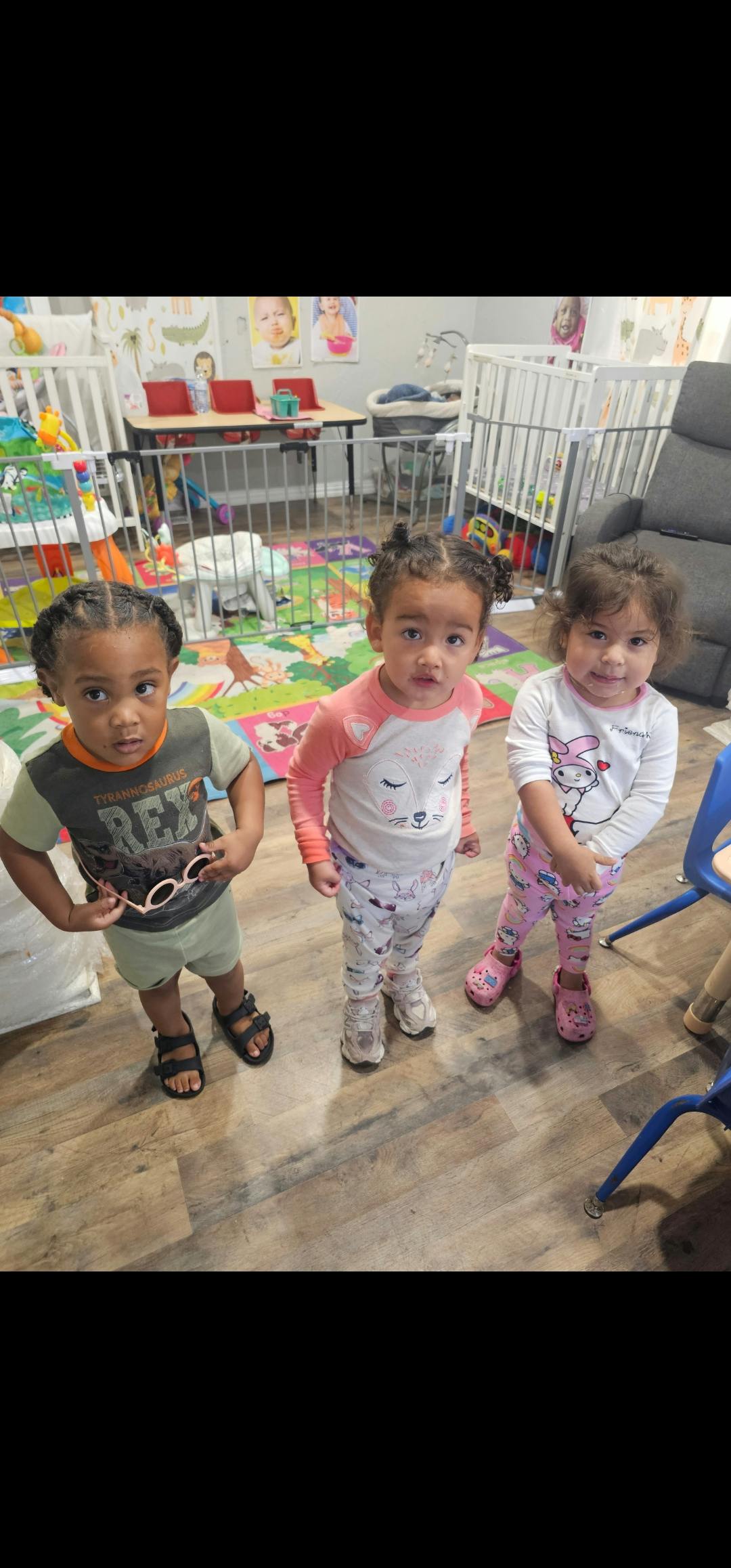 Three young children standing in a room with play equipment