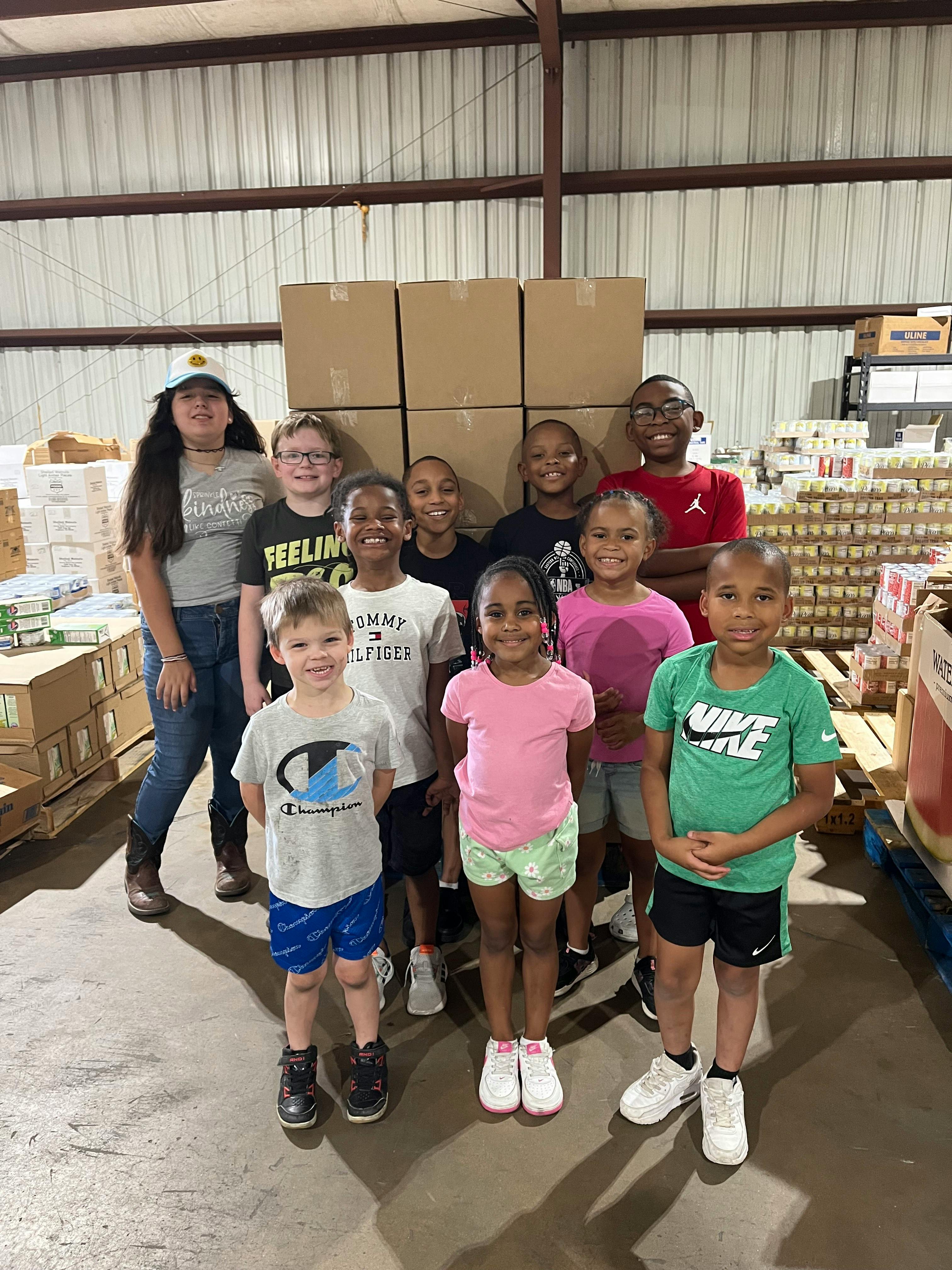 Group of children and teens standing in front of stacked boxes