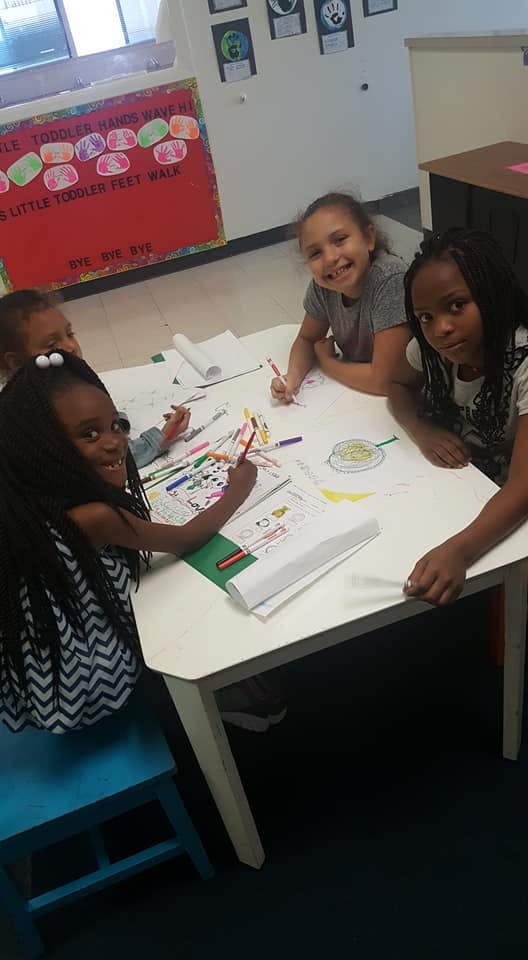 Four children drawing and coloring at a table