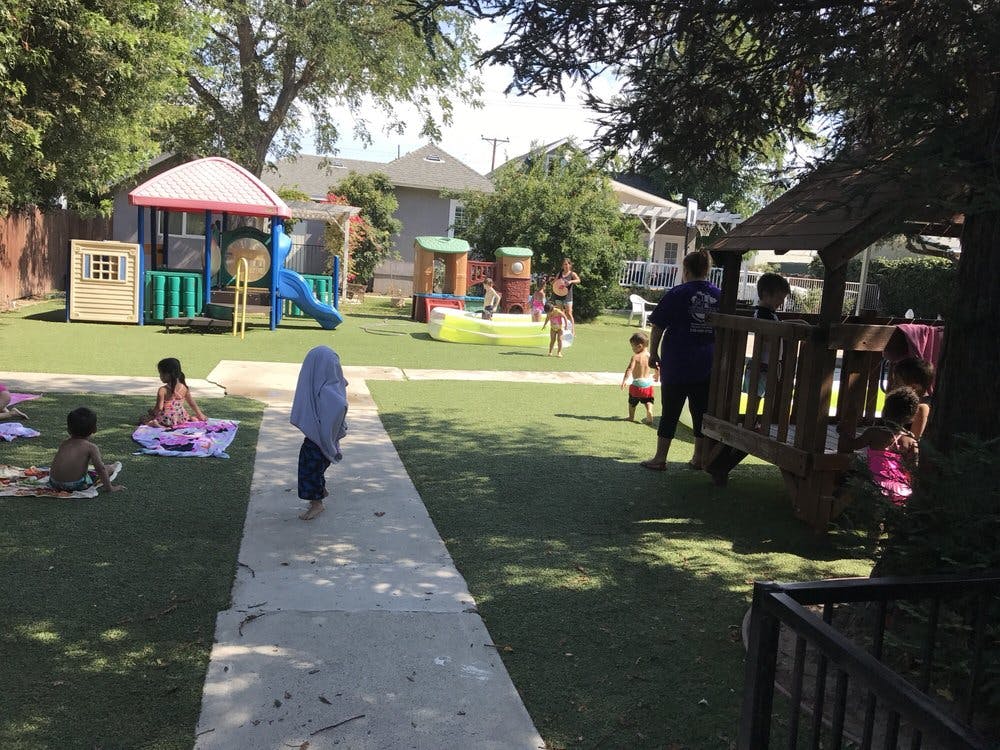 Children playing on a grassy playground with play structures