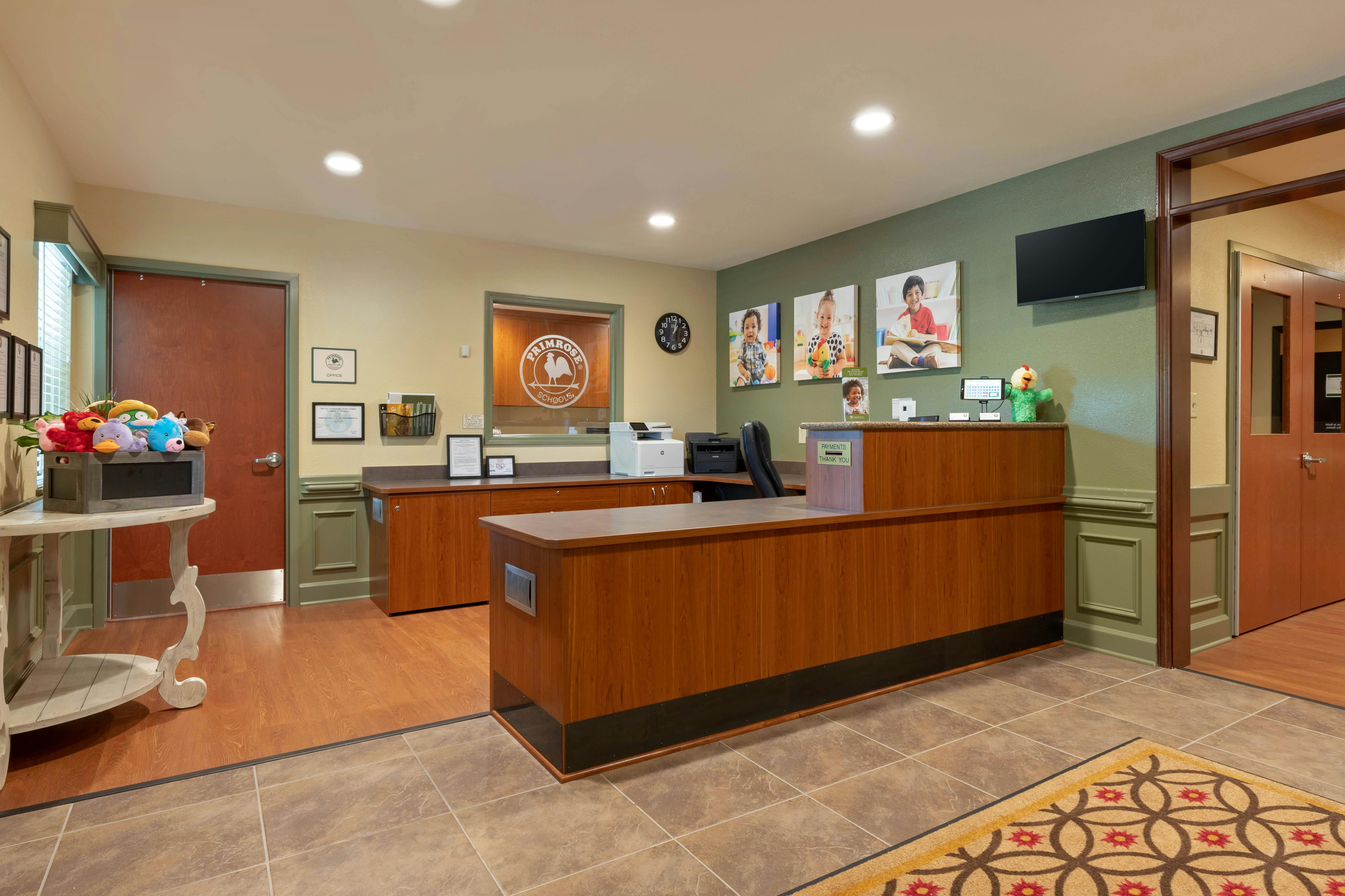 Reception desk with office equipment and child portraits in image on wall
