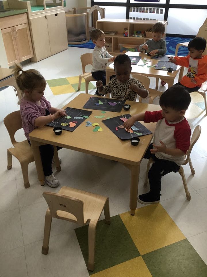 Children sitting at tables doing crafts in-class activities