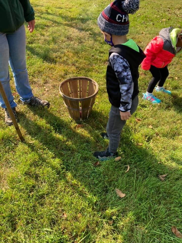 Two children and an adult standing in grass next to a basket