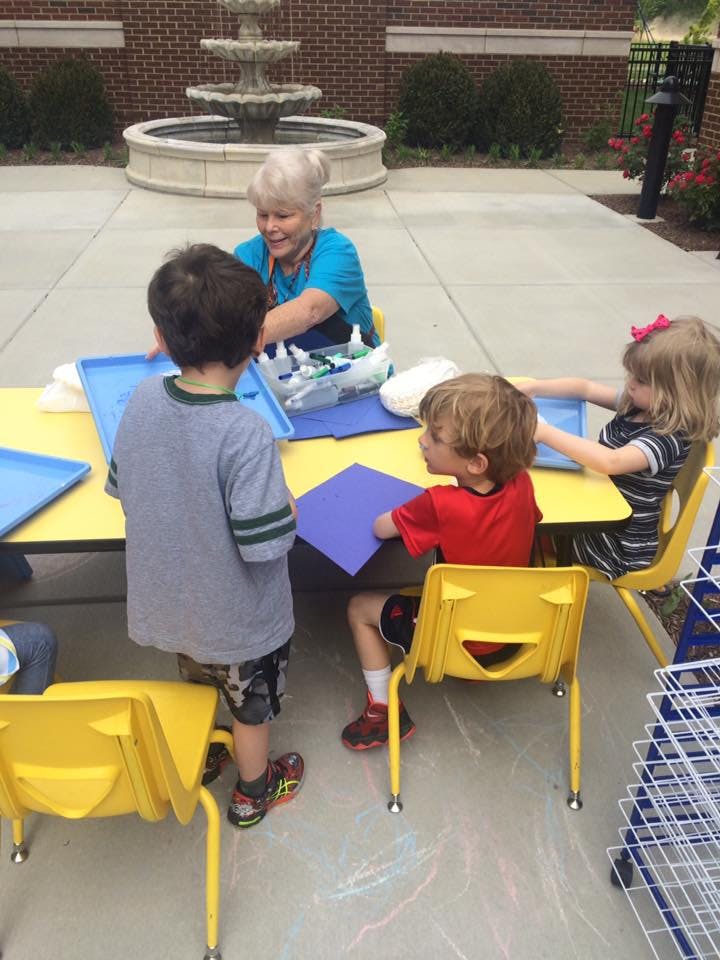 Adult and three children at a table with craft supplies