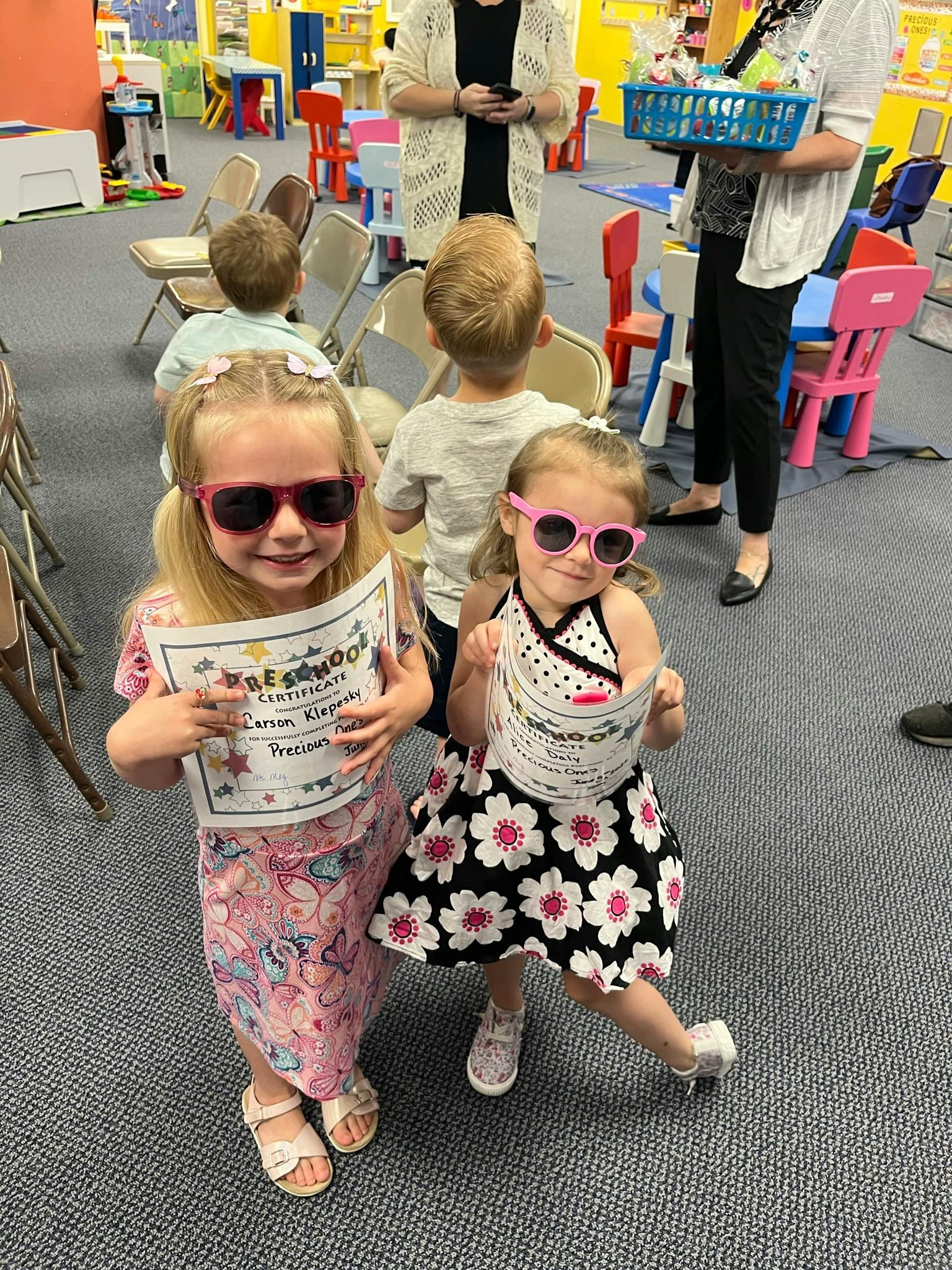 Two children wearing sunglasses holding certificates