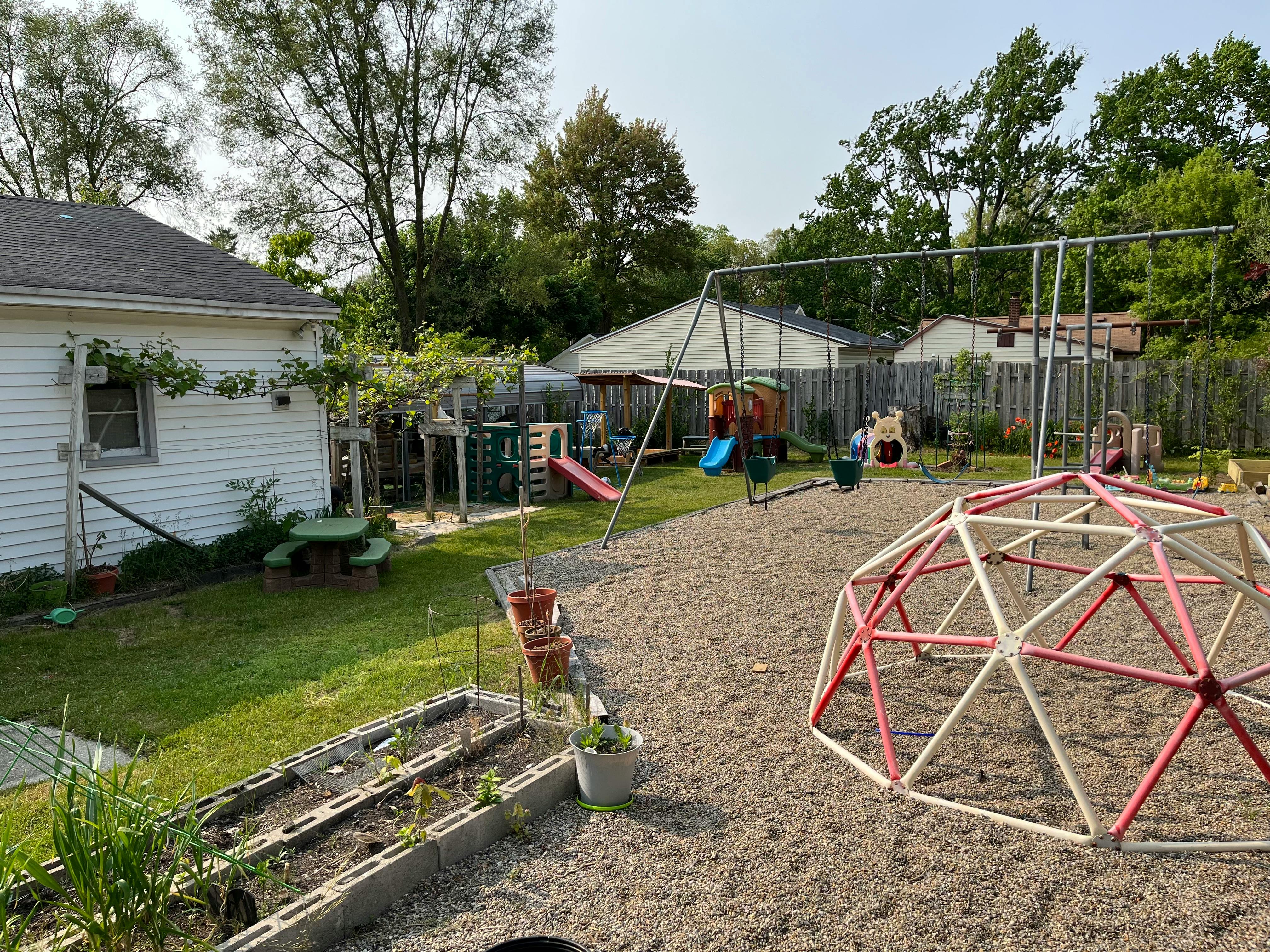 Backyard with a swing set, slide, and climbing dome
