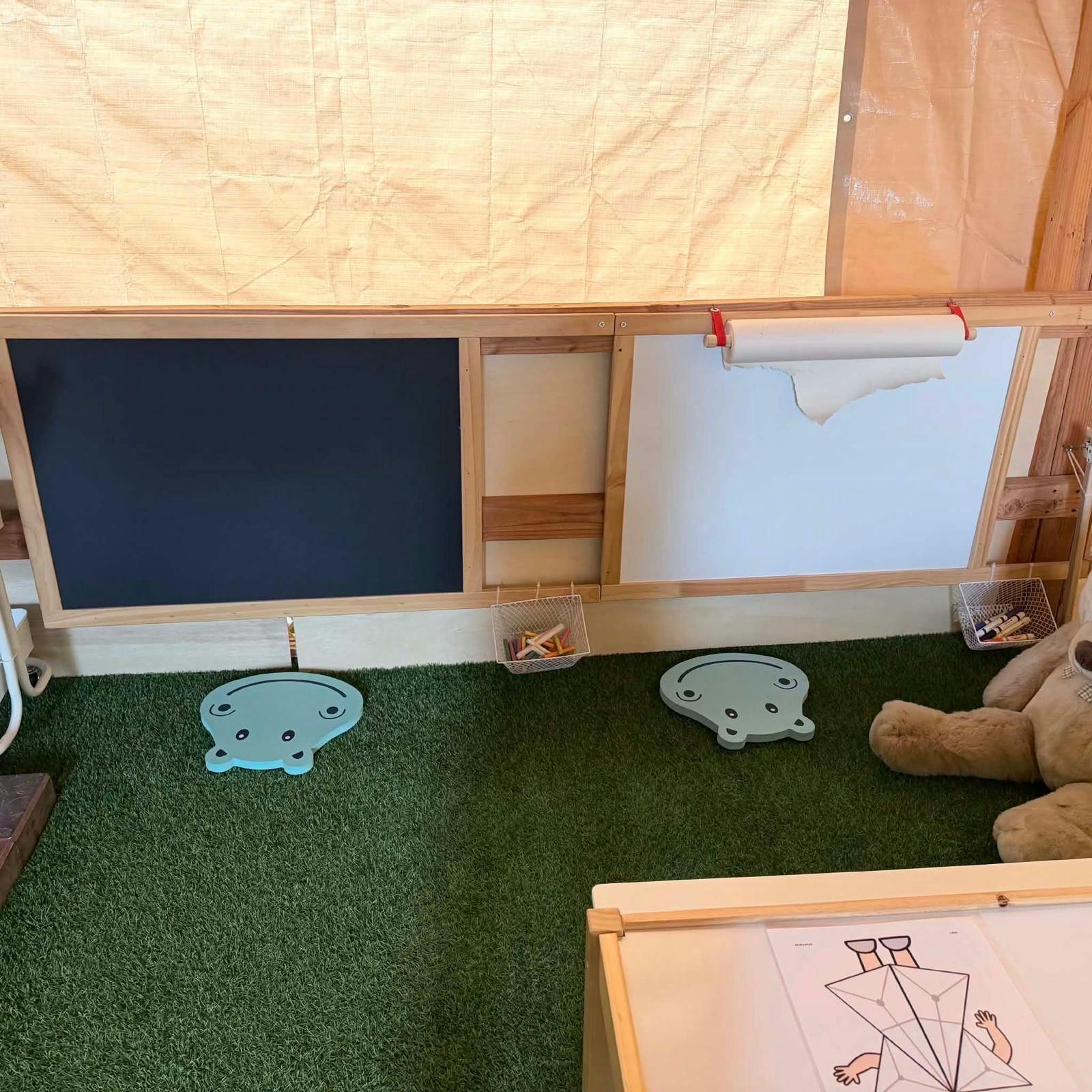 Child activity area with a chalkboard and whiteboard on a grassy floor